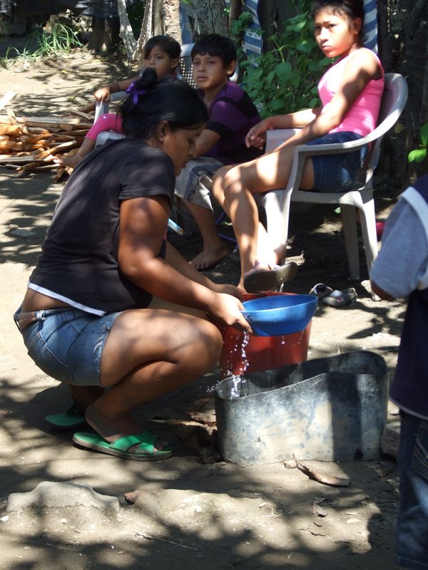 The mom from our first home visit here getting water from her neighbor’s - her house has no water, and this water is not safe for drinking but they share with each other