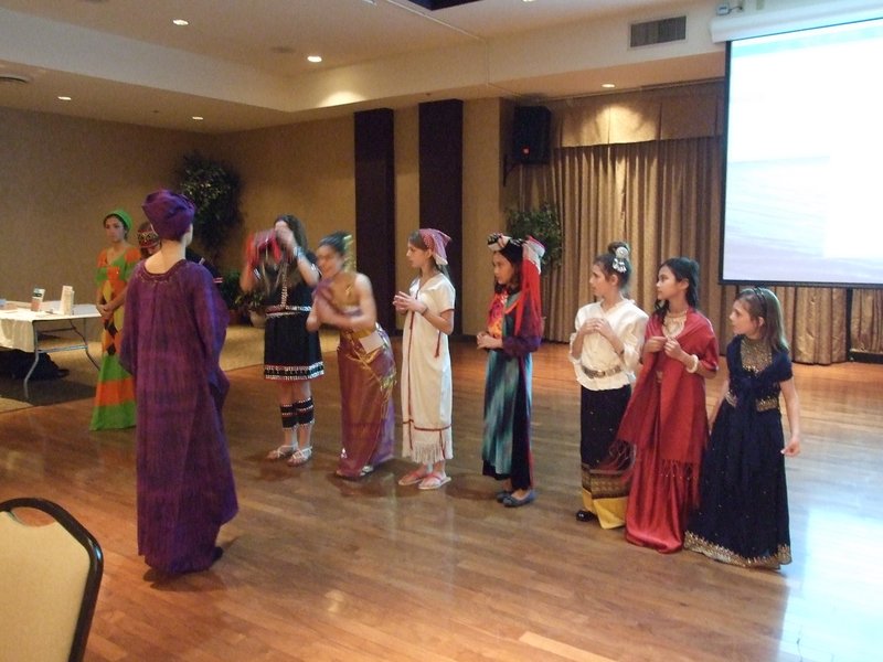 Children dressed in the traditional costumes of the nine countries they serve